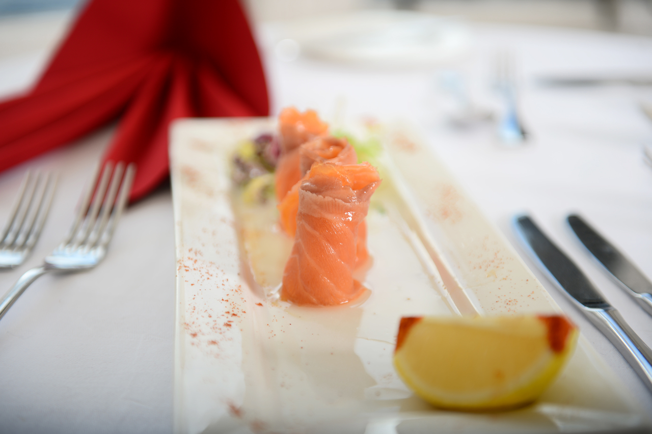 A PR photo of a salmon dish served up with lemon on a white plate